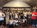 Il gruppo di partecipanti con libri e tazze in biblioteca